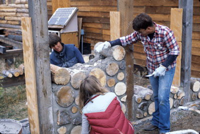 Participants use cottonwood ends to build a cordwood masonry guesthouse during an Earthwood Building School workshop.